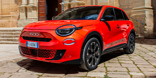 Rød Fiat 600e står parkert på brostein