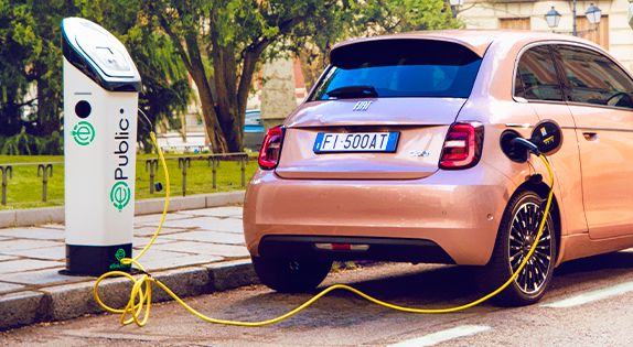 Rosa Fiat 500e sett bakfra står parkert og er tilkoblet lader